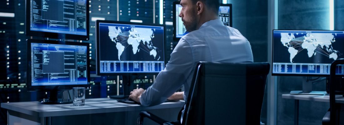 Technical Controller Working at His Workstation with Multiple Displays. Displays Show Various Technical Information. He's Alone in System Control Center.